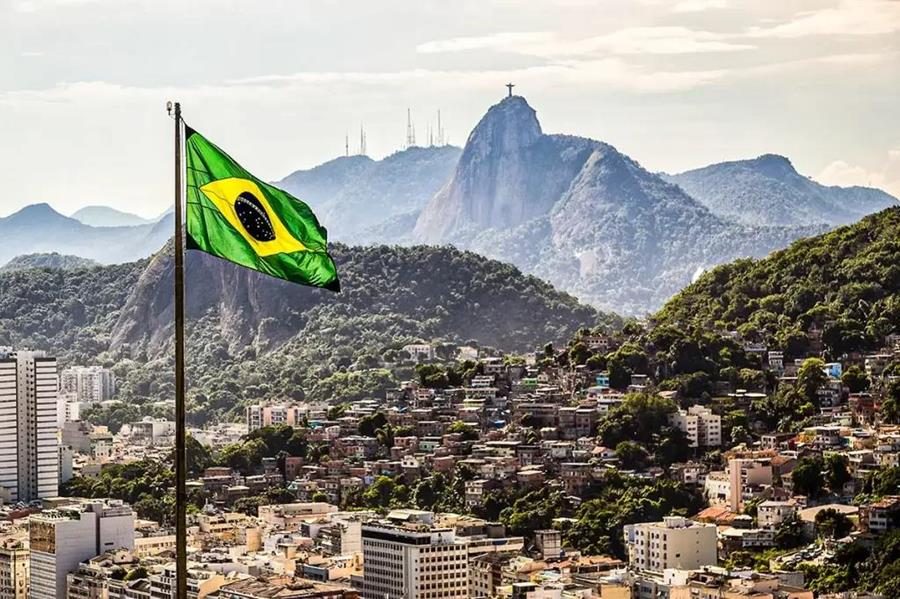 Bandeira do Brasil tremulando no alto do Morro da Babilônia, com o Pão de Açúcar ao fundo